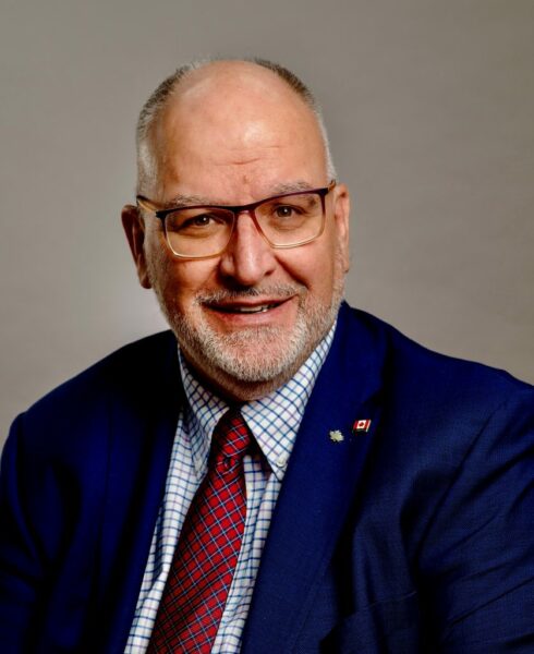Paul-Claude Bérubé est homme chauve avec des lunettes, veston et cravate.